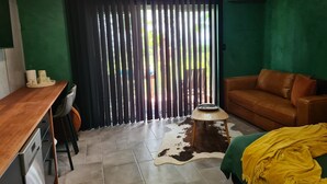A room with a wooden desk, a leather sofa, a cowhide rug, and a green wall.
