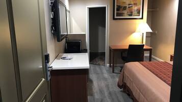 A hotel room with a bed, desk, chair, and a television mounted on the wall.