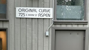 Een gebouw met een bord waarop staat 'ORIGINAL CURVE 725 E MAIN ST ASPEN' en een bord met de tekst 'HONDEN NIET TOEGELATEN'.