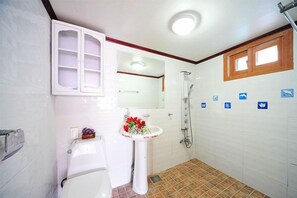 A bathroom with a toilet, sink, mirror, shower, and tiled walls. - Star Song Pension (Incheon)