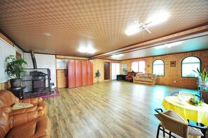 A spacious room with wooden flooring, a fireplace, a sofa, and a dining table. - Star Song Pension (Incheon)