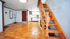 Un vaste espace de vie agrémenté d’un escalier en bois et d’une cuisine située au fond de la pièce.