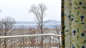 Une vue depuis un balcon, avec des arbres sans feuilles et un paysage lointain.