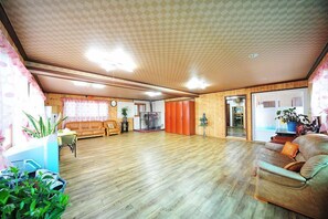 A spacious living room with wooden flooring, a sofa, a coffee table, and a glass door leading to another room. - Star Song Pension (Incheon)