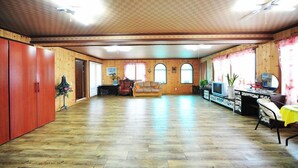 Une pièce spacieuse avec un plancher en bois, un canapé, une télévision et un bureau avec une chaise.