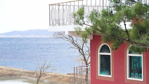 Un bâtiment doté d’un balcon donnant sur une étendue d’eau et sur une côte lointaine.