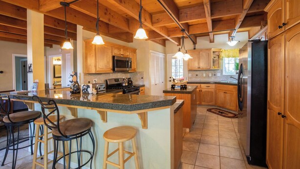 A spacious kitchen with wooden cabinets, a large island with bar stools, and modern appliances. - Beautiful & Cozy Cabin. Perfect Location, Kid Friendly. Free Starlink WIFI. (Cold Springs)