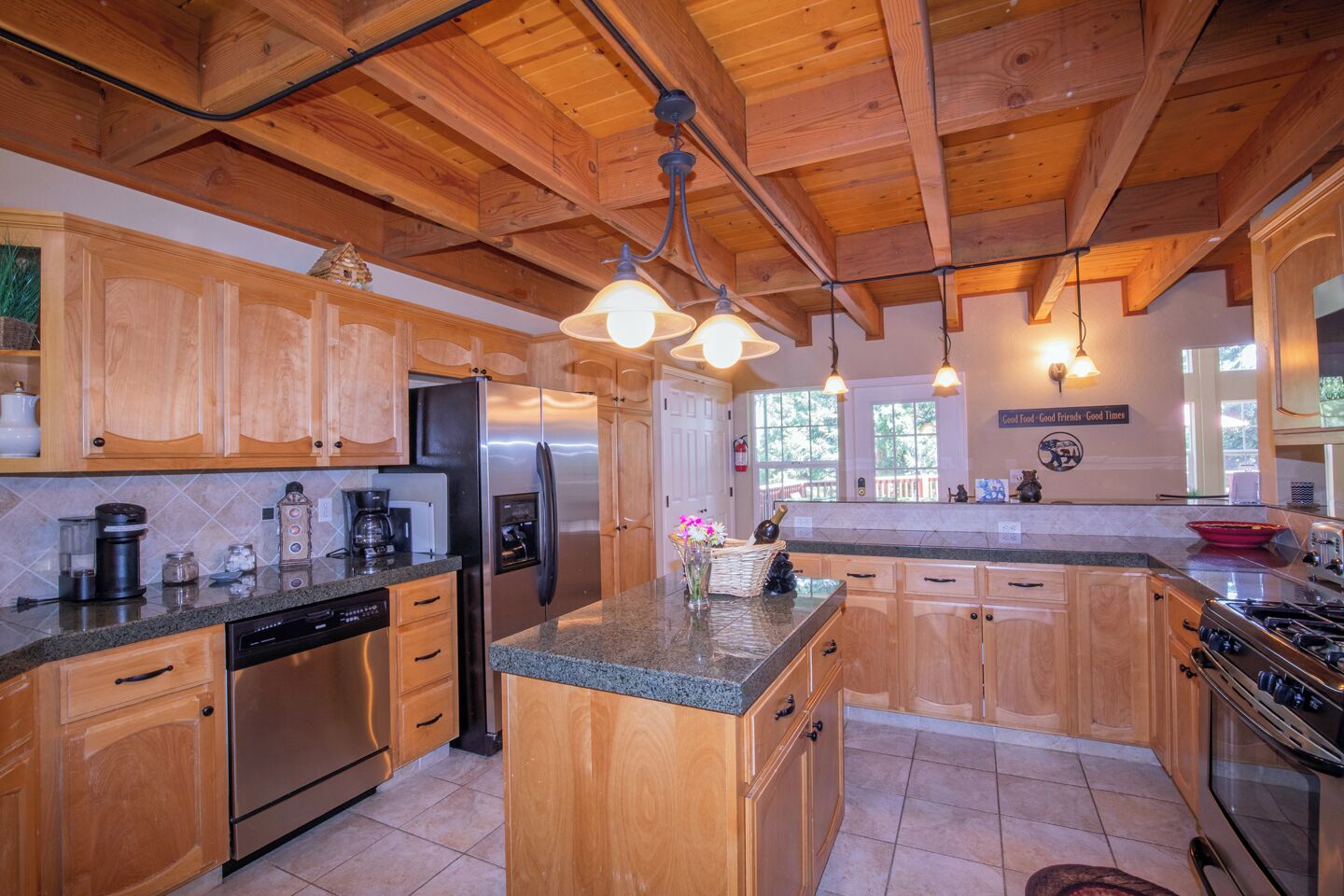 A spacious kitchen with wooden cabinets, granite countertops, stainless steel appliances, and pendant lighting.