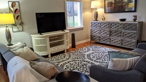 A living room with a TV, sofa, and a patterned rug.