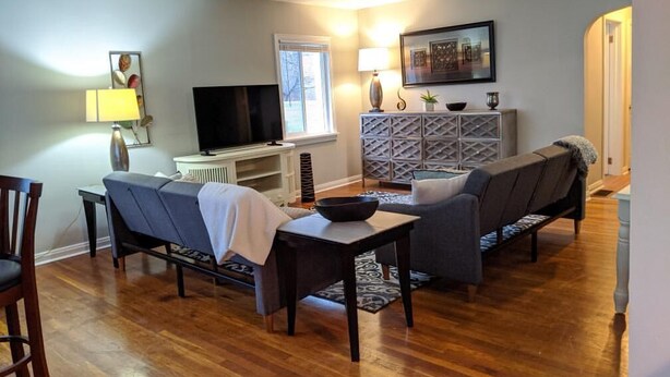 A living room with a sofa, chairs, a TV, a lamp, and a console table.