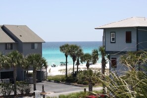 A beachfront property with two-story houses, a sandy beach, and palm trees.