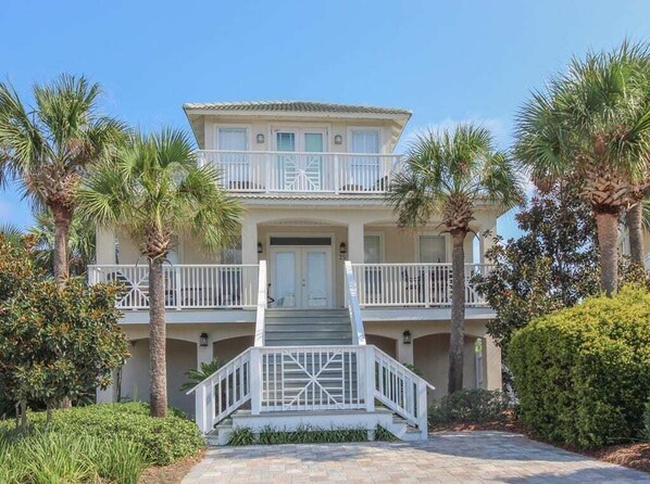 A two-story building with a balcony, surrounded by palm trees and a well-maintained garden.