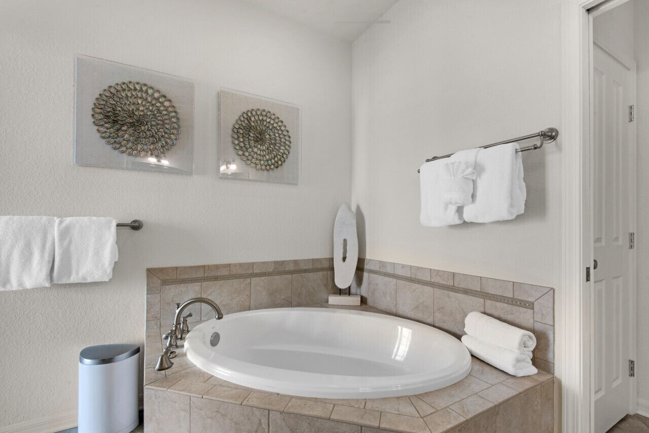 A modern bathroom with a freestanding bathtub, a towel rack with multiple towels, and two wall-mounted decorative mirrors.