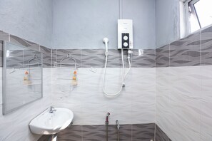 Un baño con lavamanos blanco, un cabezal de ducha de mano, grifo empotrado y un perchero.