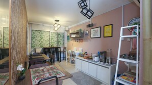 Un'area pranzo con un tavolo in legno, sedie e una pianta di orchidea decorativa. È presente una zona cucina con mobili, un lavello e diversi oggetti da cucina.