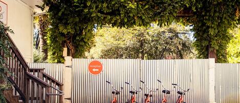 A reception area with a corrugated metal fence, a wooden staircase, and a row of bicycles parked in front.