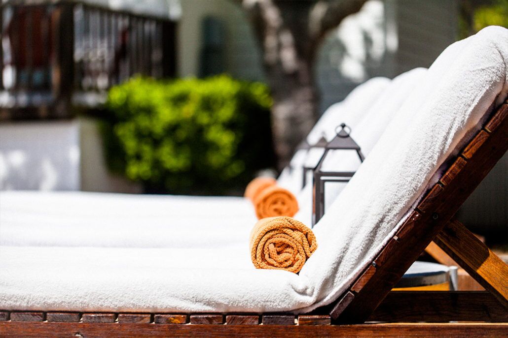A sun lounger with a white towel and an orange towel.
