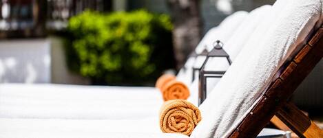A sun lounger with a white towel and an orange towel.