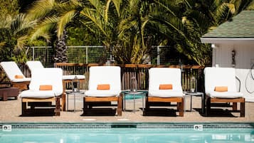 Una piscina al aire libre, sombrillas, sillones reclinables de piscina