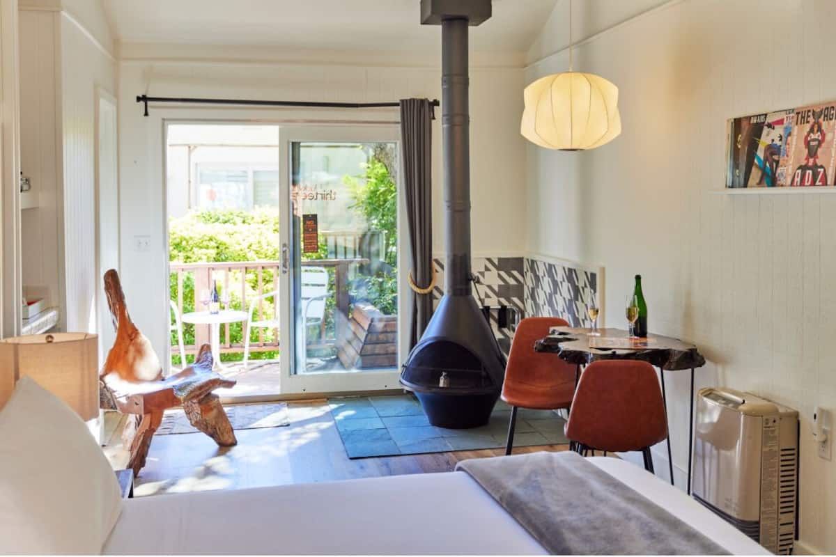 A hotel room with a bed, a table with chairs, a fireplace, and a view of the outdoors.