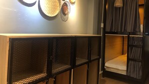 Una habitación con literas, un estante montado en la pared con cestas tejidas y una lámpara colgante.