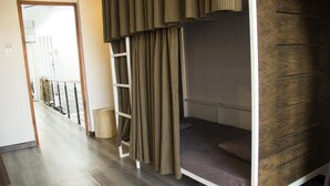 Habitación con literas, suelo de madera y vistas a un balcón.
