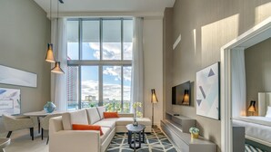 Un salon moderne avec un canapé, une table basse et une grande fenêtre donnant sur la ville.