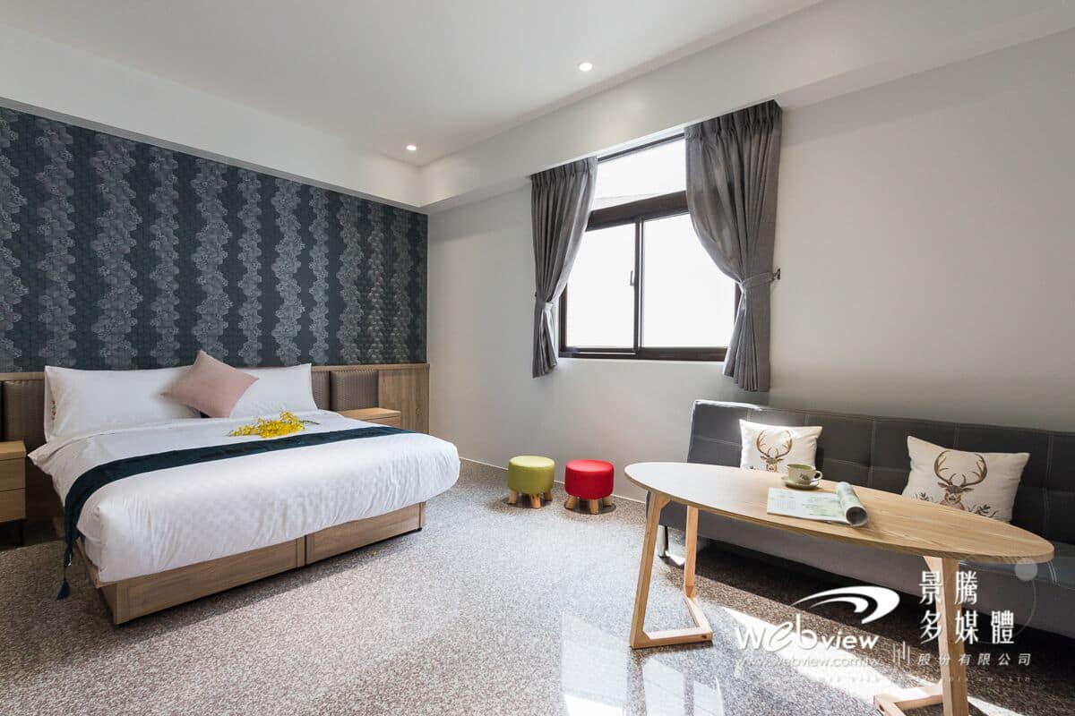 A modern hotel room with a large bed, a small table, and a sofa.