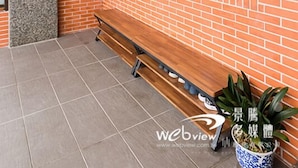A brick-walled interior with a wooden bench, a potted plant, and a window with a view. - Play Inn (Dongshan)