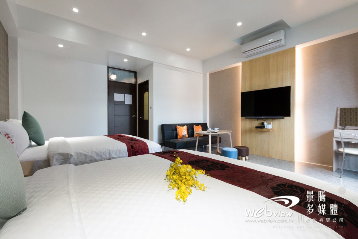 A modern hotel room with a large bed, a desk, a flat-screen TV, and a sofa.