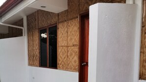 Un bâtiment doté d’un patio carrelé, d’une porte en bois et de plantes en pot.