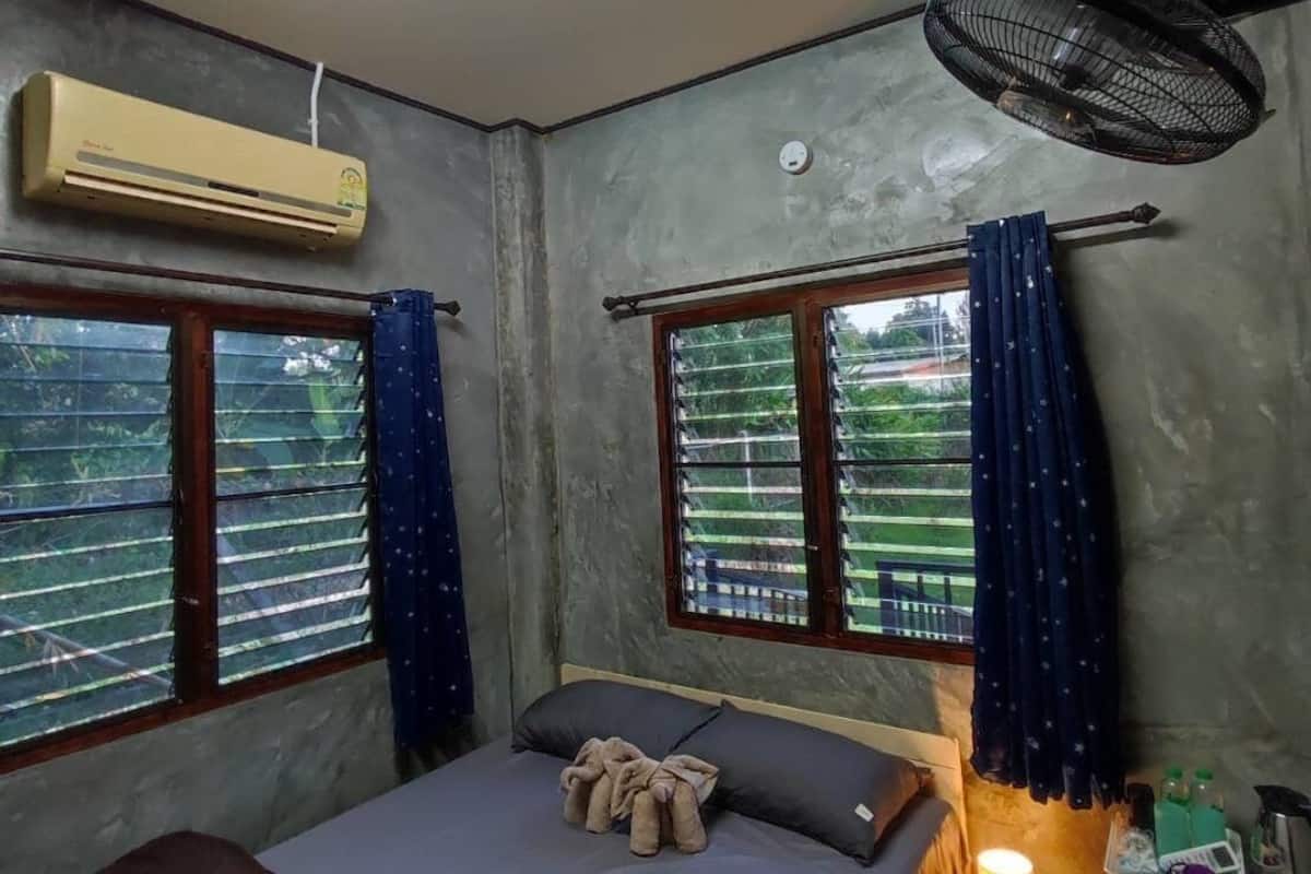 A small, dimly lit room with a bed, a heater, and a fan.
