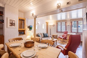 Et spiseområde med et træbord dækket til fire personer, en sofa og en rød stol.