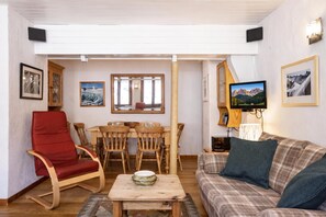 A cozy living room with a red chair, a wooden dining table with chairs, a sofa, and a television. - Résidence Igloo 12 ski in/ski out at Le Tour, Le Tour (Argentière), France (Le Tour (Argentière))