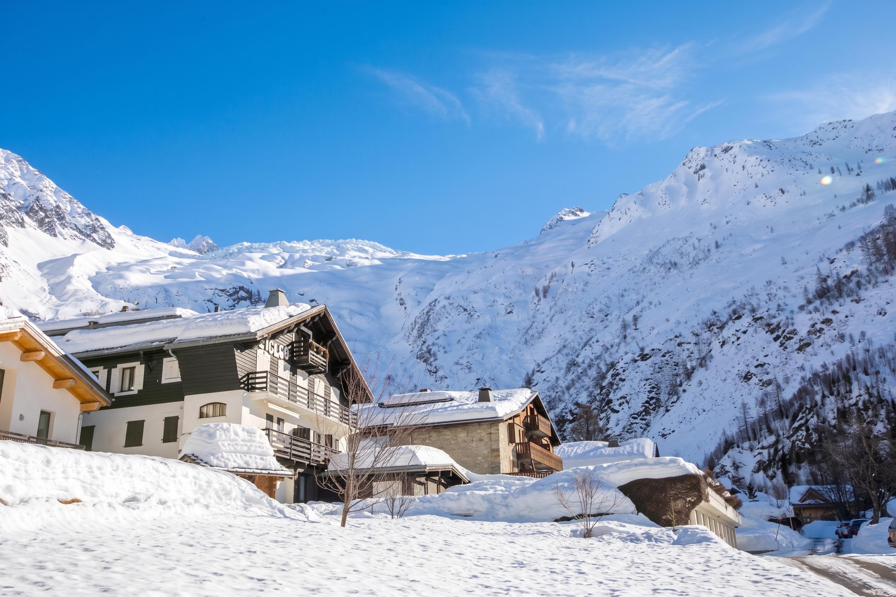 A snow-covered mountain village with traditional wooden buildings and a clear blue sky.