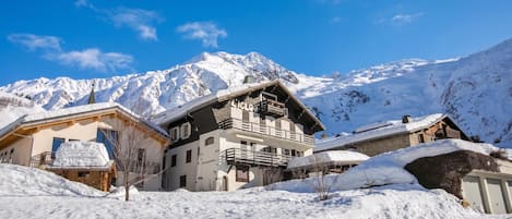 A snow-covered mountain village with traditional wooden buildings and a clear blue sky.
