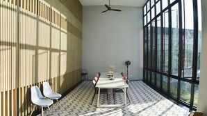 Een moderne kamer met een groot raam, twee plafondventilatoren, een tafel met stoelen en een kamer met een patroon vloer.