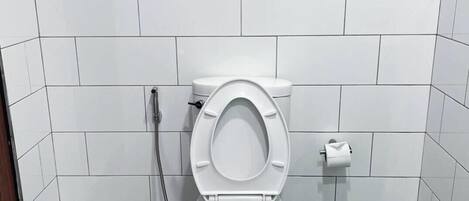 Ein kleines, sauberes Badezimmer mit weißen Fliesen, einer weißen Toilette und einer Dusche.