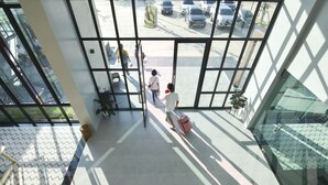 Een modern gebouw met grote ramen en uitzicht op geparkeerde auto's.