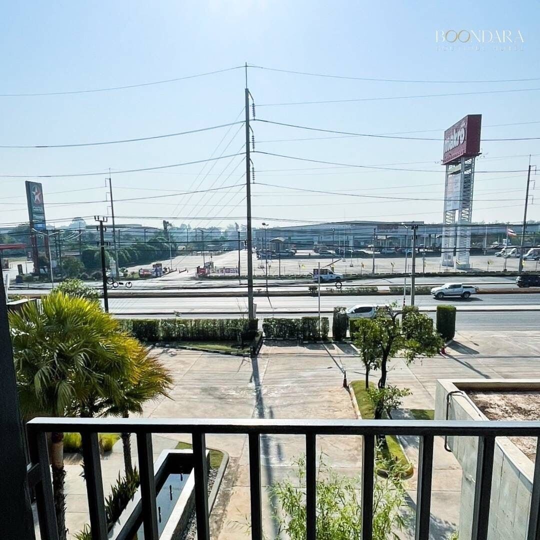 Une vue depuis un balcon donnant sur un parking, avec un ciel dégagé.