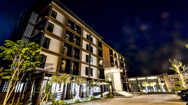 Een hotel met meerdere verdiepingen, met een modern ontwerp, balkons en een goed verlichte entree.