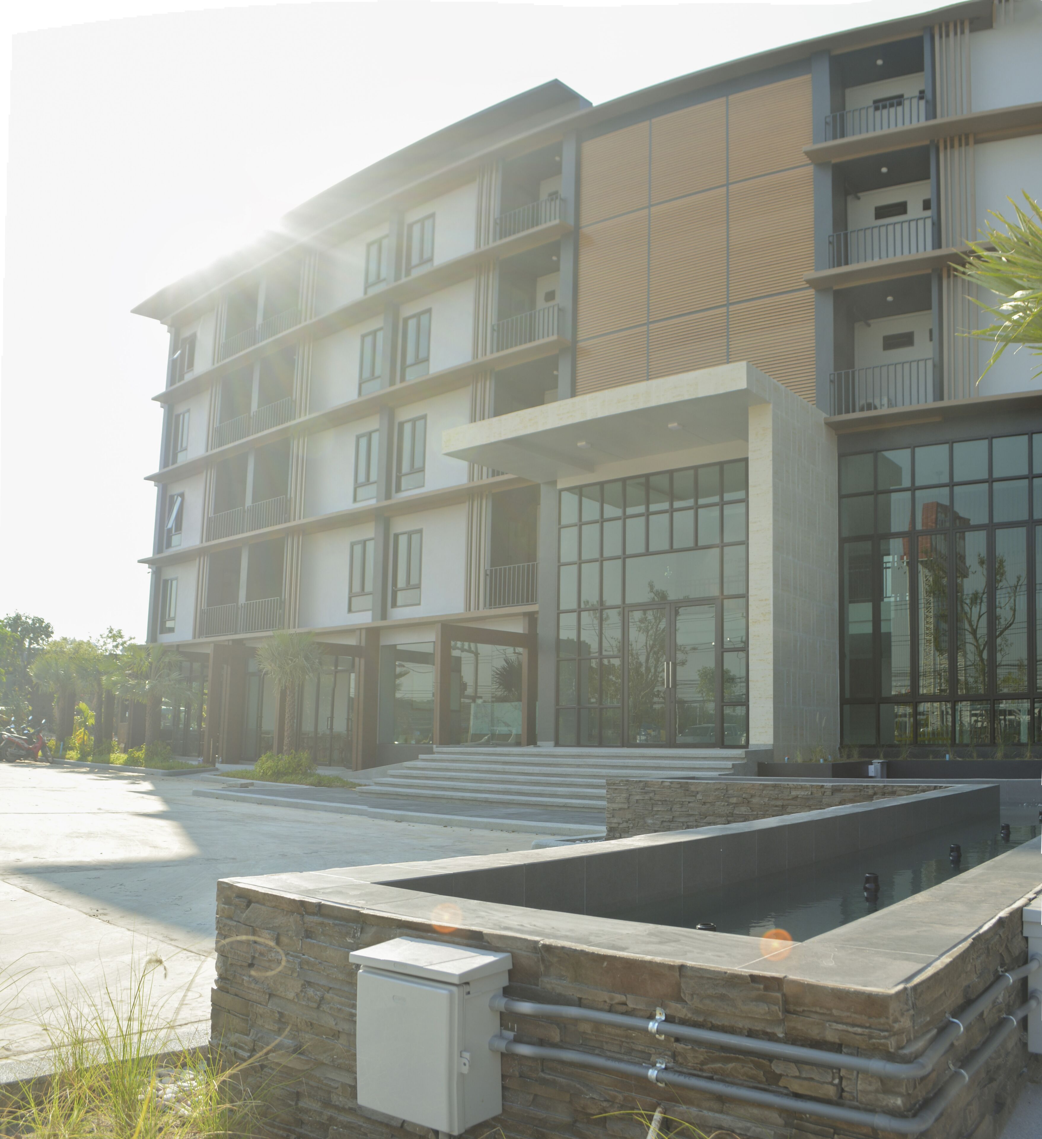 A multi-story building with a modern architectural design, featuring balconies, large windows, and a stone facade.