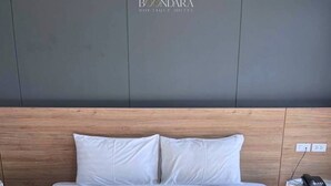 Een hotelkamer met een groot bed, twee kussens en netjes opgevouwen handdoeken op het bed.