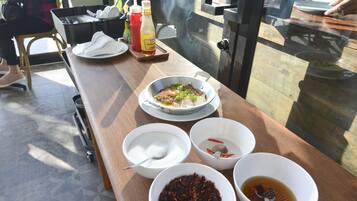 A dining table with various dishes and condiments, including a bowl of soup, a plate of food, and several condiments.