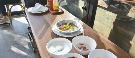 A dining table with various dishes and condiments, including a bowl of soup, a plate of food, and several condiments.