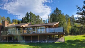 Une maison à deux étages dotée d’un balcon, de grandes fenêtres et d’une pelouse bien entretenue.