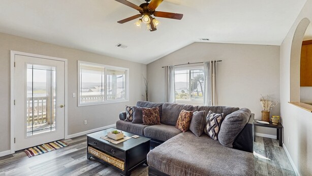 A spacious living room with a sectional sofa, a coffee table, and a ceiling fan.