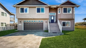 A two-story residential house with a garage, a front porch, and a well-maintained lawn.