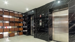 A modern elevator with a metallic finish and a marble wall with white veins. - Skyview Setiabudi Premium (Medan)