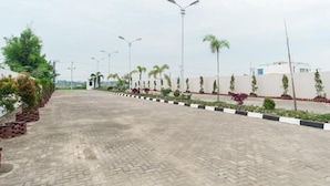 A paved pathway lined with street lamps and small trees, leading to a white building with a flat roof. - Skyview Setiabudi Premium (Medan)